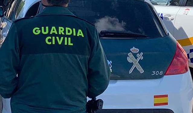 Archivo - Un agente de la Guardia Civil junto a un vehículo oficial.